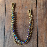 Gold chain with colorful beads on a wooden surface