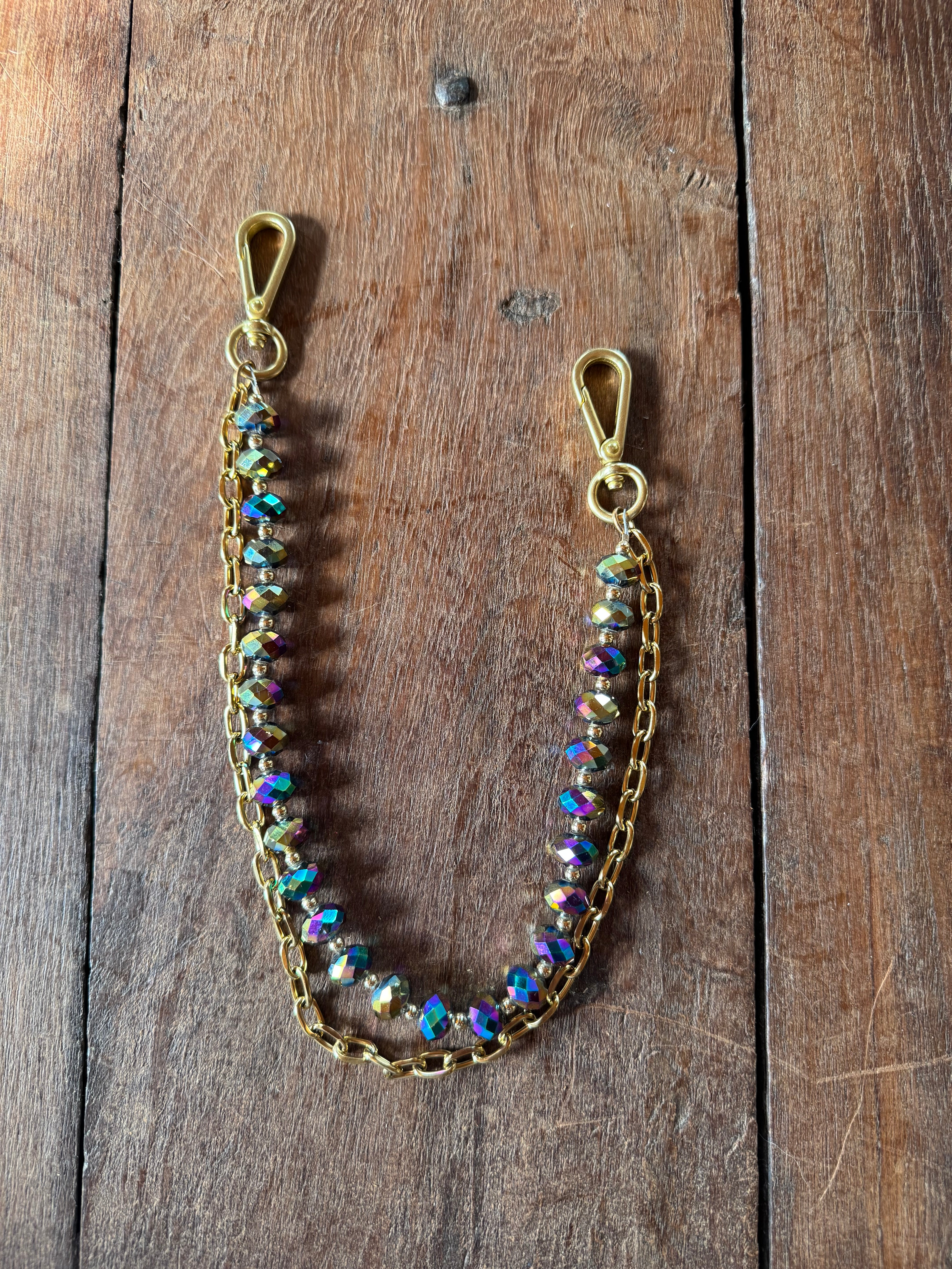 Gold chain with colorful beads on a wooden surface