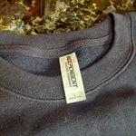 Close-up of a dark gray sweatshirt with an 'Independent Trading Company' label on a textured surface.