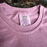 Close-up of a pink garment with a Comfort Colors label on a marble surface