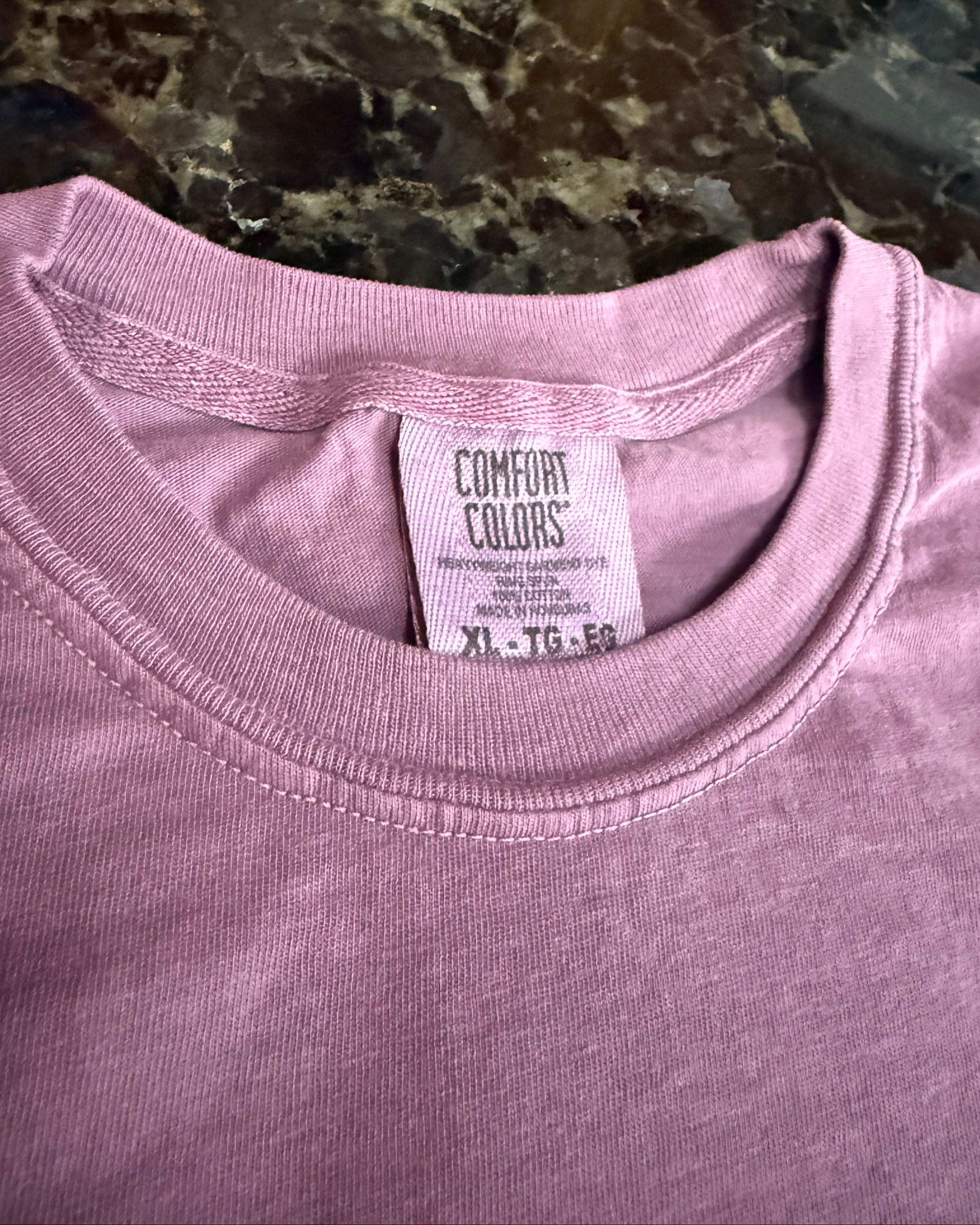 Close-up of a pink garment with a Comfort Colors label on a marble surface