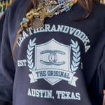 Women wearing blue crewneck with colorful jewelry on at Leatherandvodka in Round Top Texas