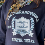 Women wearing blue crewneck with colorful jewelry on at Leatherandvodka in Round Top Texas