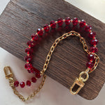 LAV x JForks Red Crystal Chain with clips to attach to handbag, sitting on wood and marble surface. 