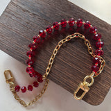 LAV x JForks Red Crystal Chain with clips to attach to handbag, sitting on wood and marble surface. 