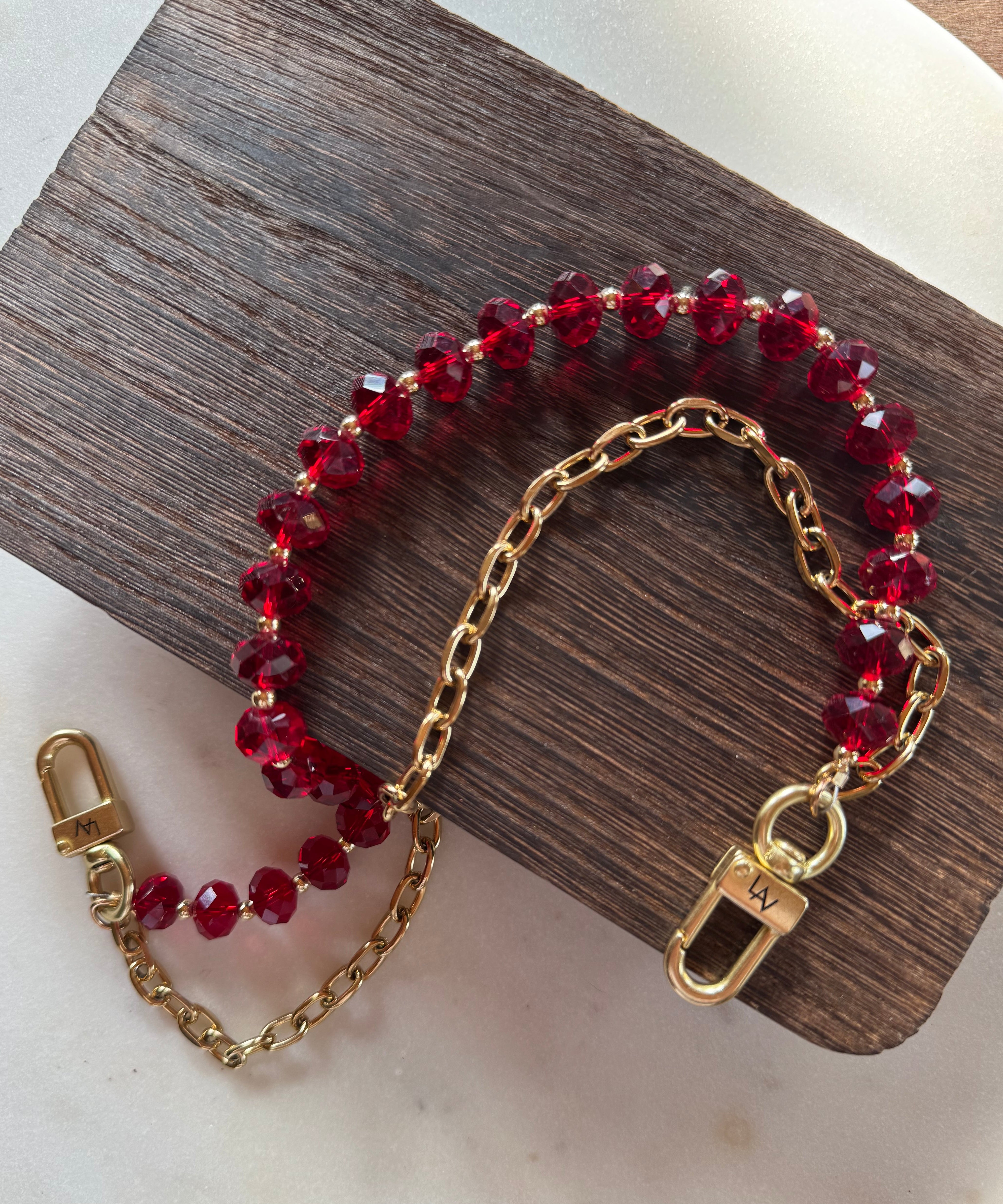 LAV x JForks Red Crystal Chain with clips to attach to handbag, sitting on wood and marble surface. 
