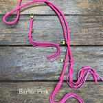 barbie pink colored leather bag strap with gold clasps on a wooden surface