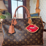 Designer handbag with a unique lip-shaped tag on a wooden surface