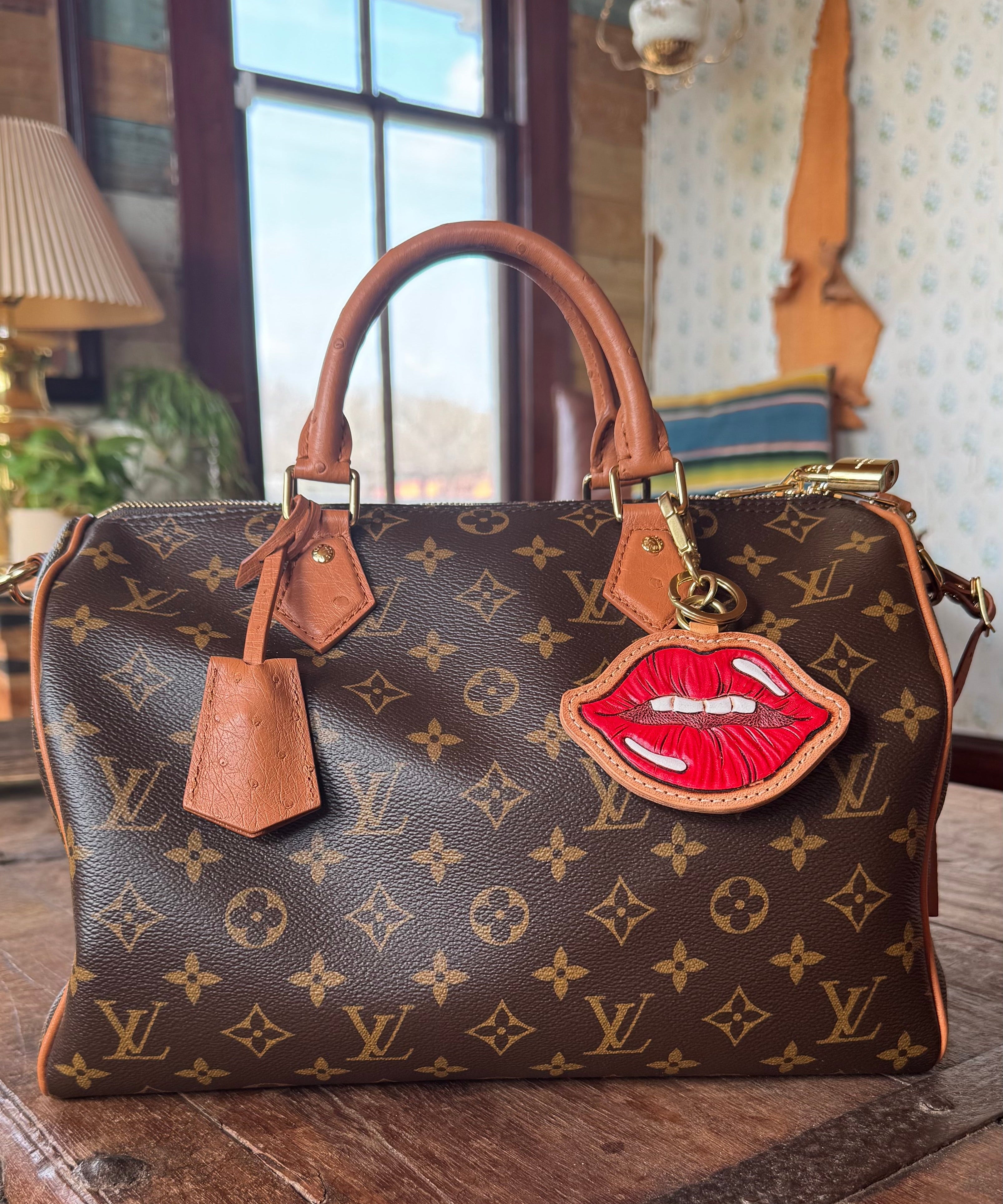 Designer handbag with a unique lip-shaped tag on a wooden surface