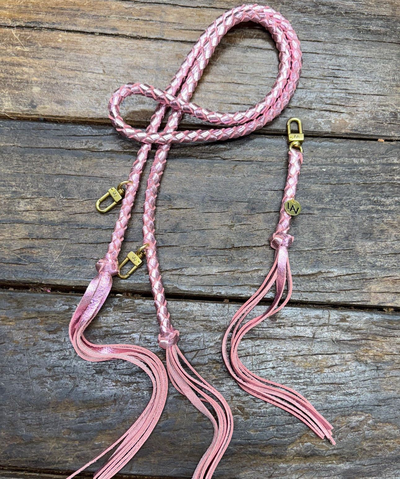 Metallic Pink Bag Strap, made with braided leather with matching snap on key chain, laying on wooden table. 