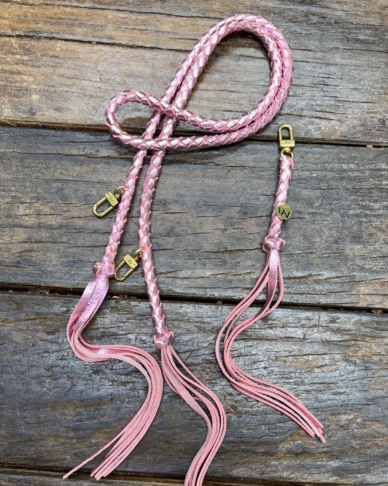 Metallic Pink Bag Strap, made with braided leather with matching snap on key chain, laying on wooden table. 