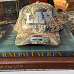 Camouflage cap with 'LAV' branding on top of books