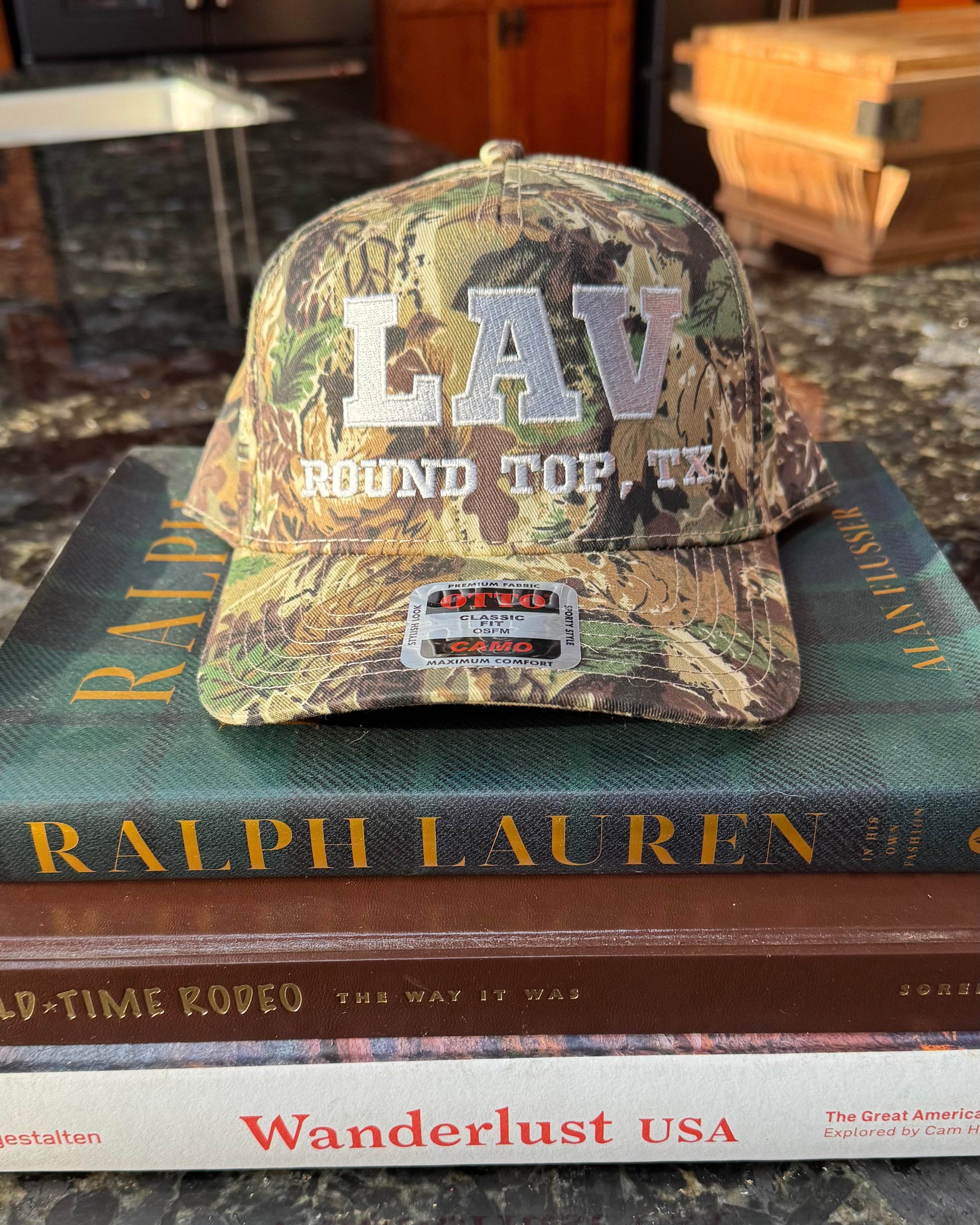 Camouflage cap with 'LAV' branding on top of books