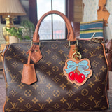 Designer handbag with decorative charm on a wooden surface