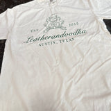 White shirt with words leatherandvodka on a dark surface