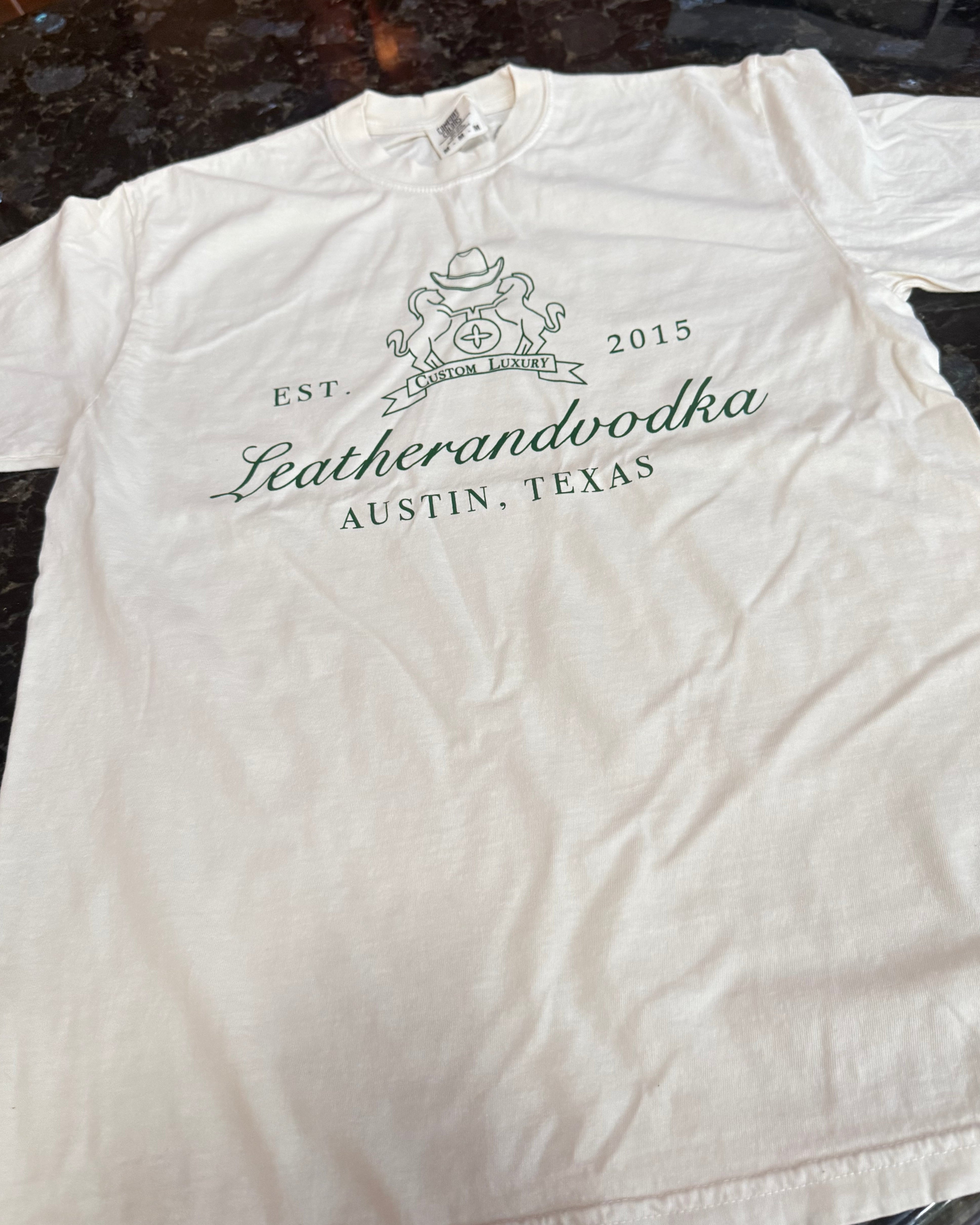 White shirt with words leatherandvodka on a dark surface