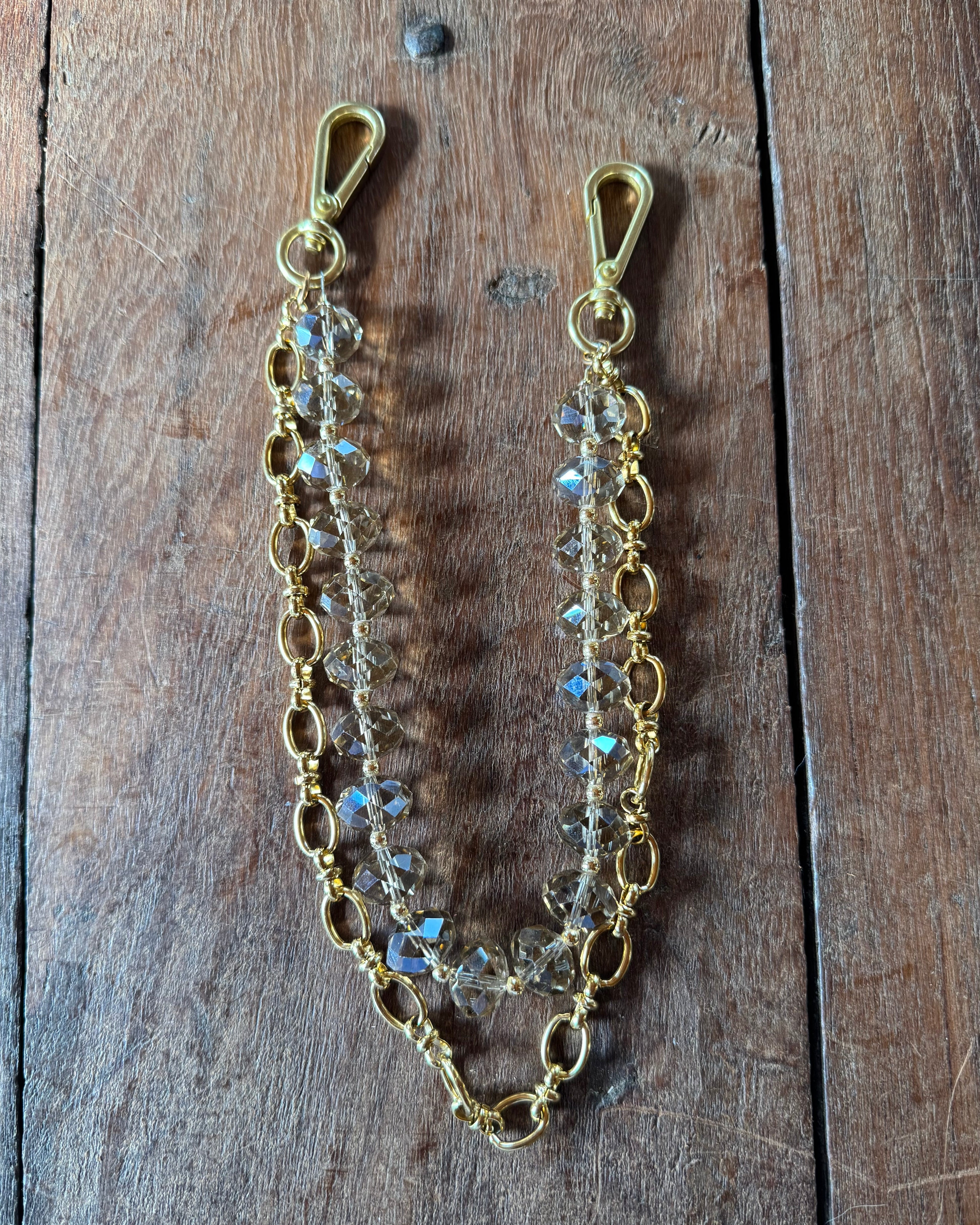 Gold luxury handbag chain with crystal-like beads on a wooden surface, collab of jforks and leatherandvodka