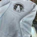 Gray crewneck with a logo on a dark surface