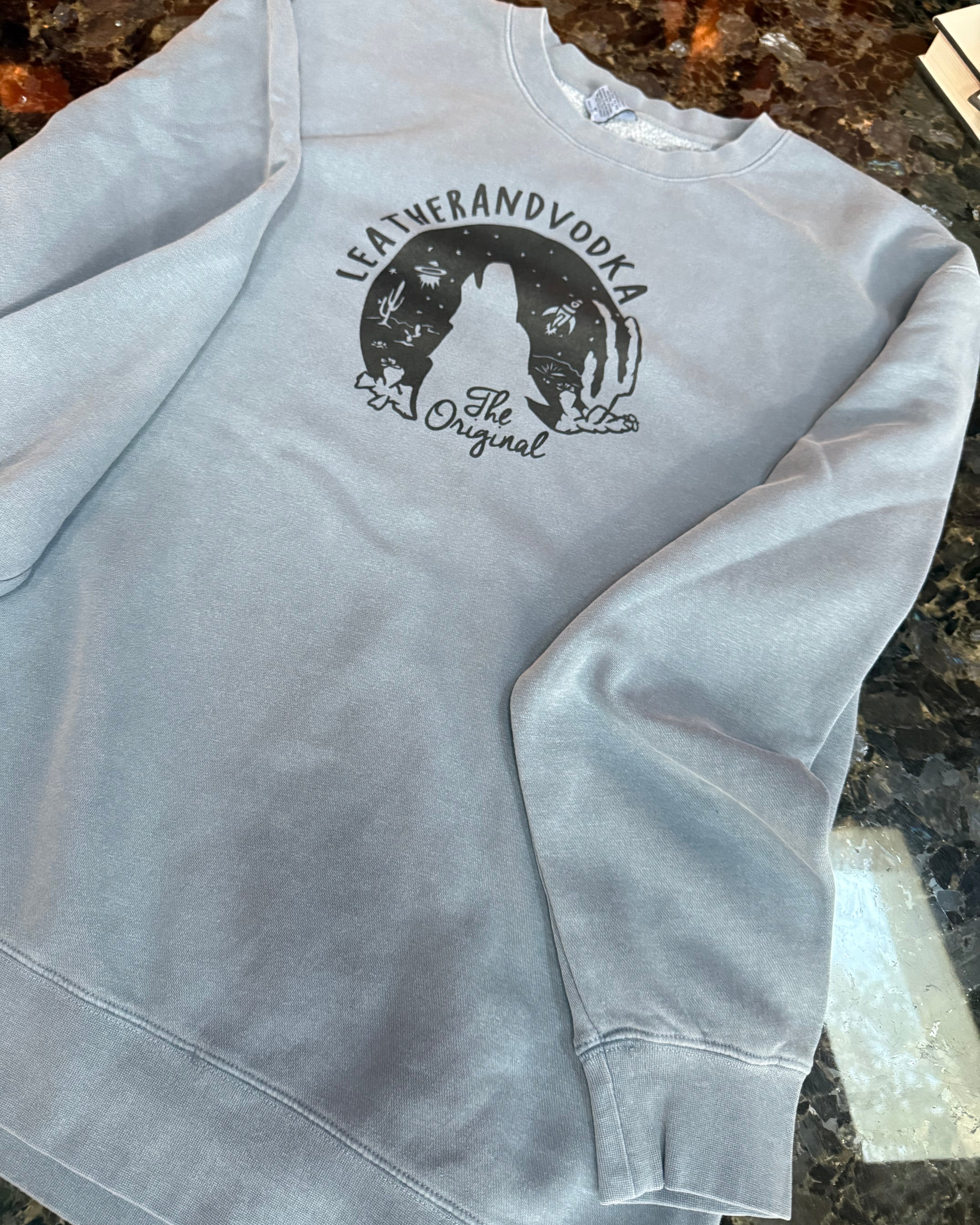 Gray crewneck with a logo on a dark surface