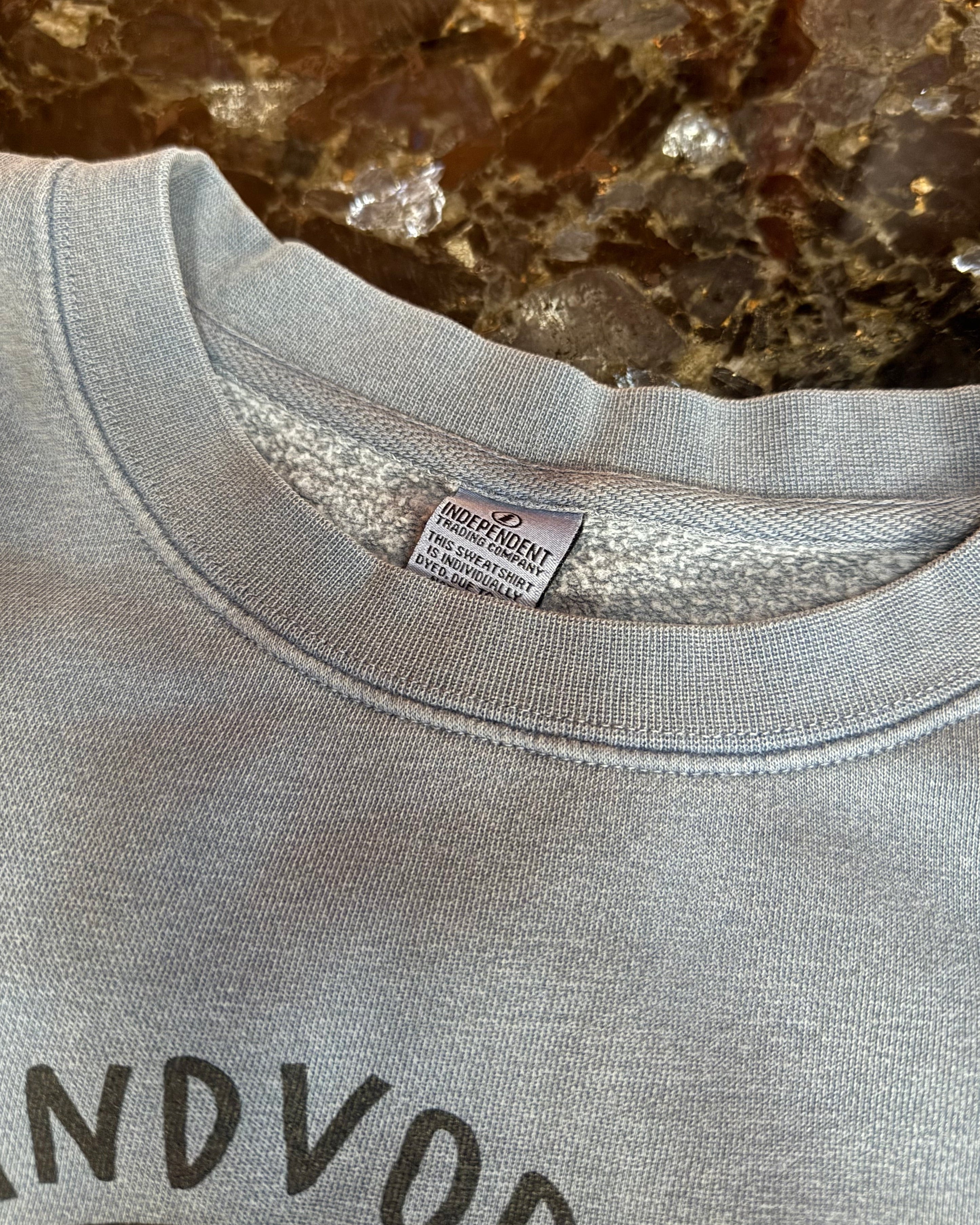 Gray sweatshirt with a brand label on a marble surface